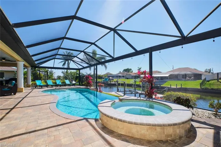 View of pool with a water view, a pool with connected hot tub, a lanai, and a patio area