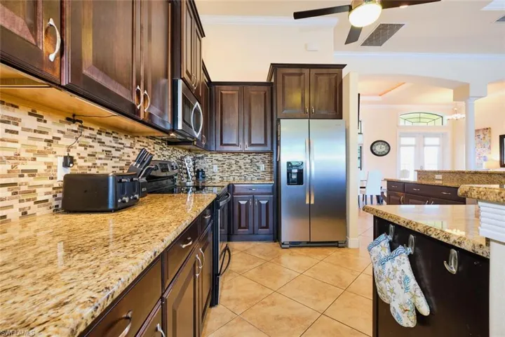 Kitchen with light tile patterned flooring, a ceiling fan, appliances with stainless steel finishes, and ornamental molding
