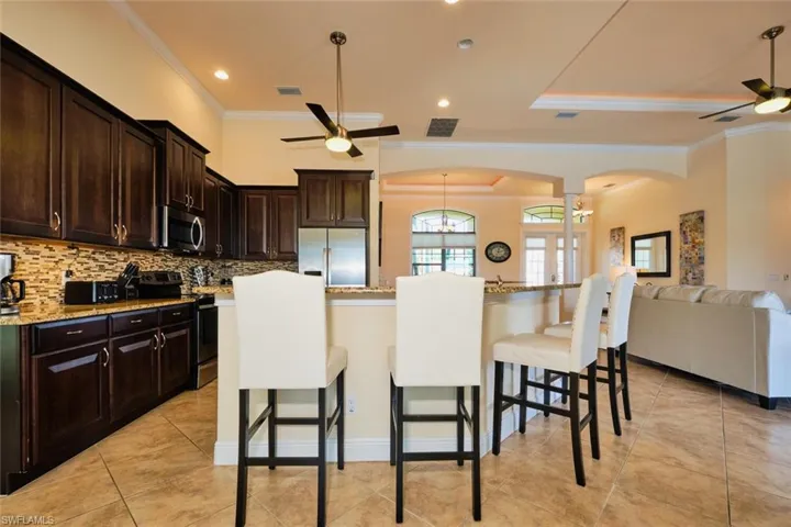 Kitchen featuring visible vents, arched walkways, appliances with stainless steel finishes, a breakfast bar area, and ceiling fan