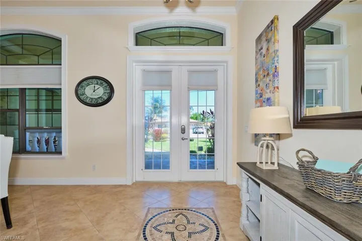 Foyer featuring light tile patterned floors, french doors, crown molding, and baseboards