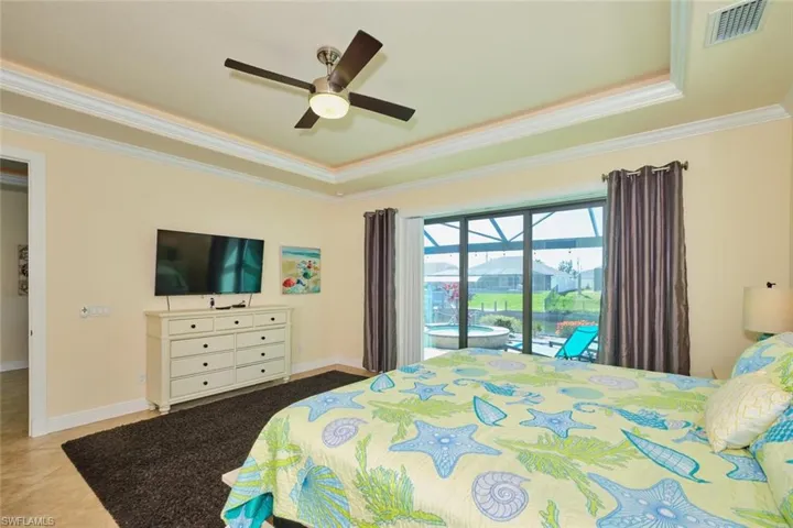 Bedroom with a tray ceiling, visible vents, access to exterior, and crown molding