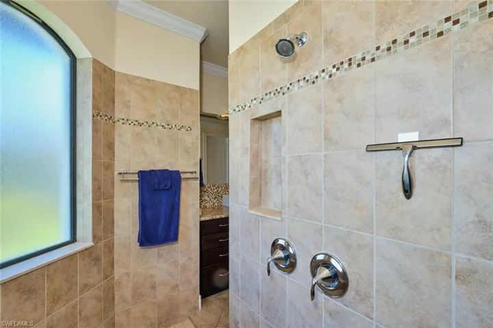 Bathroom featuring a tile shower and ornamental molding