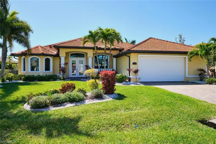 Mediterranean / spanish home with french doors, a tile roof, driveway, and stucco siding