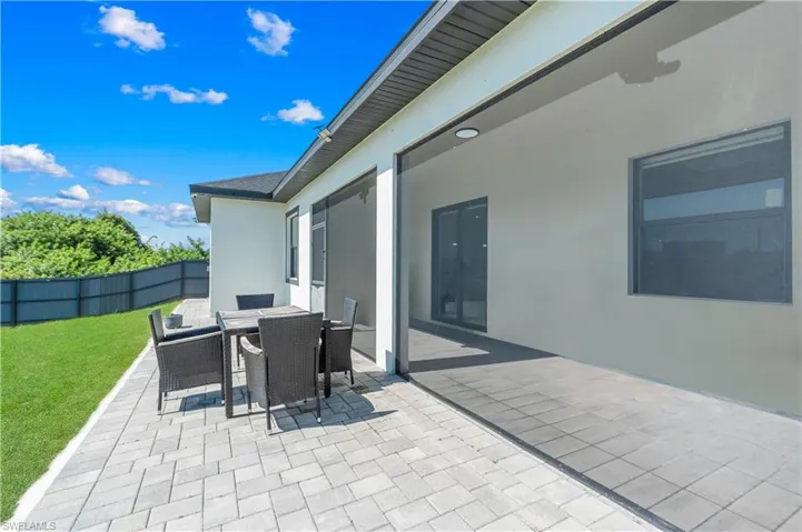 Spacious paver patio with a screened lanai area, offering a direct walkout to a manicured lawn