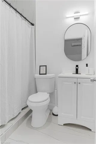 Modern bathroom featuring a white vanity with panel-style doors, a rectangular undermount sink, and a matte black faucet