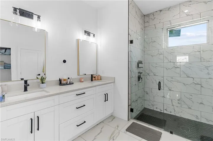 Dual vanity with light-toned countertops and white cabinetry, complemented by matte black fixtures