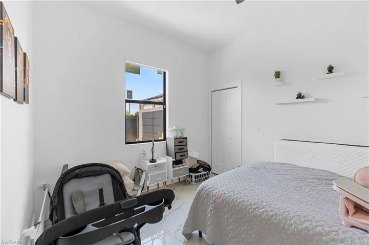 Bedroom featuring white walls, bright window, tile flooring, and closet with bifold doors