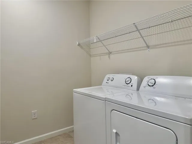 Laundry area with light tile patterned floors and washer and clothes dryer