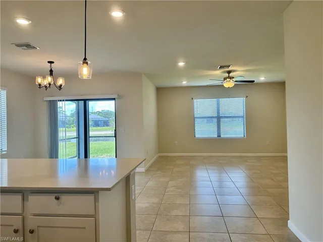 Kitchen with light tile patterned floors, hanging light fixtures, recessed lighting, white cabinets, and light stone countertops