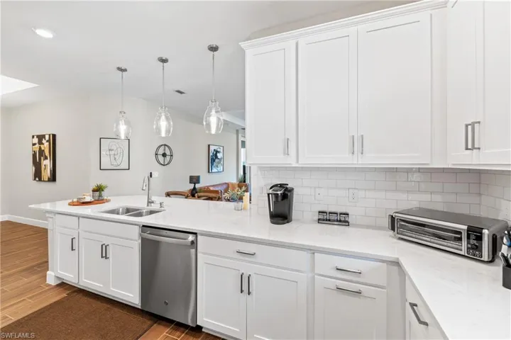 Bright kitchen featuring white shaker cabinetry, stainless steel appliances, a subway tile backsplash, and light countertops