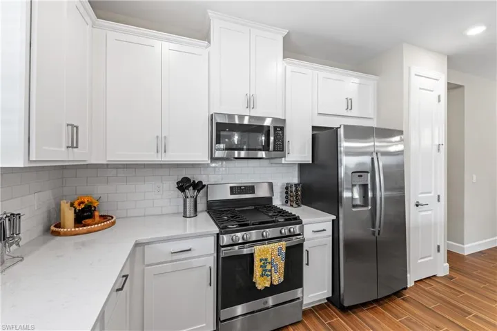 Contemporary kitchen featuring white shaker cabinetry, stainless steel appliances, a white subway tile backsplash, and light-colored countertops