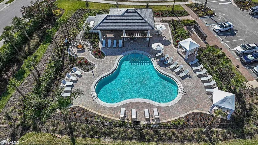 Freeform swimming pool with paver decking, an adjacent covered cabana, and multiple shaded lounge areas
