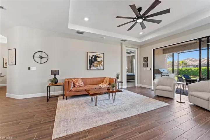 Spacious interior with wood-finish tile flooring, tray ceiling, and a contemporary ceiling fan