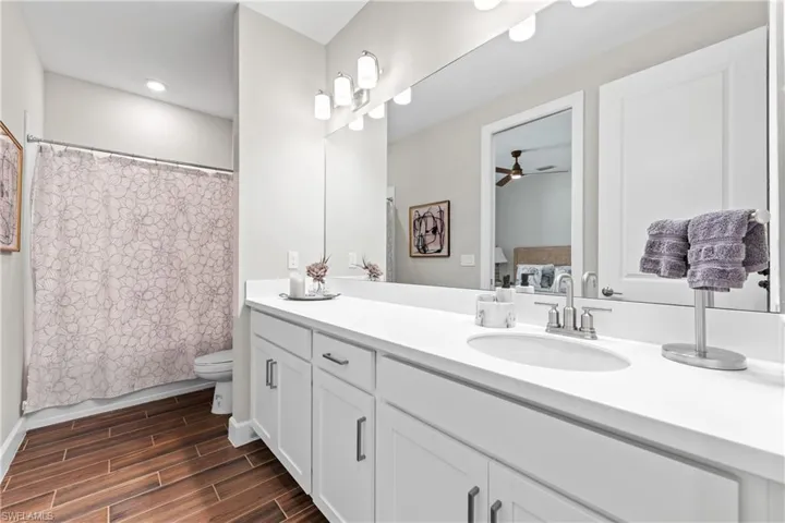 White vanity with a single undermount sink, brushed nickel faucet, and a large mirror