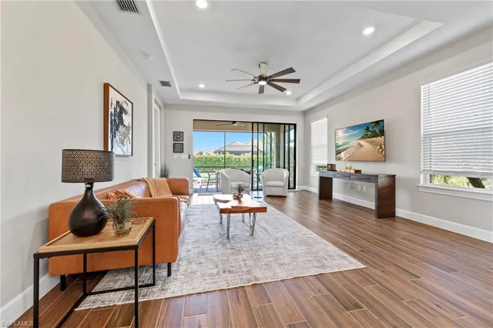Living space featuring wood-finish flooring and a tray ceiling with recessed lighting