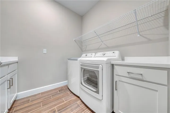 Laundry room featuring wood-finish flooring, white cabinetry, integrated countertops, and overhead wire shelving