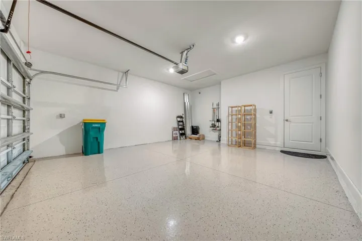Spacious garage featuring a speckled epoxy floor coating, crisp white walls, and bright overhead lighting