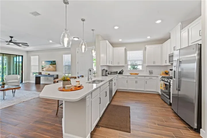 Contemporary kitchen featuring white cabinetry, stainless steel appliances, and a central island with a breakfast bar