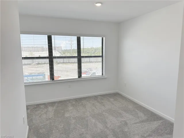 Spare room featuring light carpet and baseboards