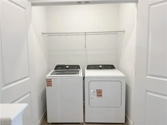 Washroom with washer and clothes dryer and baseboards