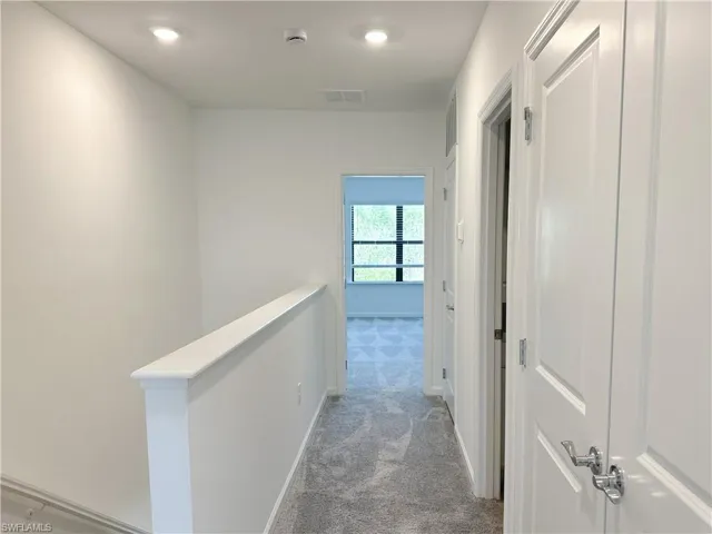 Hall featuring light colored carpet and an upstairs landing