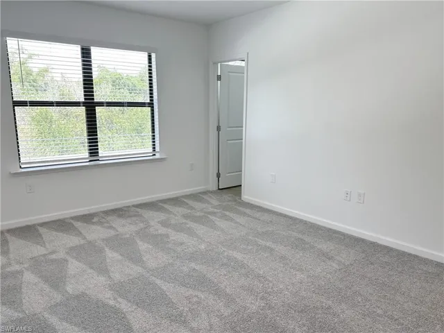 Carpeted empty room with baseboards