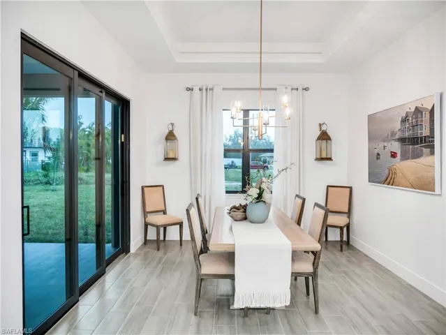 Dining space featuring wood finish floors, a tray ceiling, and a chandelier