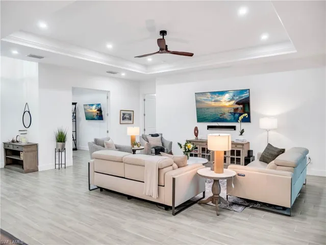 Living area featuring ceiling fan, light wood-style flooring, recessed lighting, a raised ceiling, and crown molding