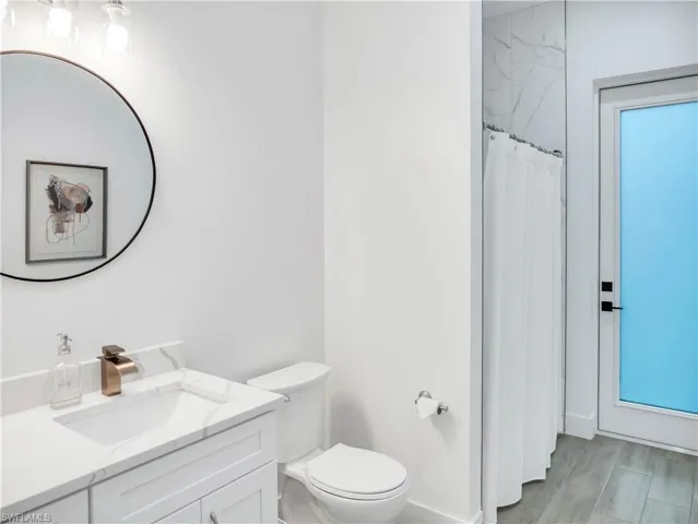 Full bathroom featuring vanity, a shower with curtain, and light wood finished floors