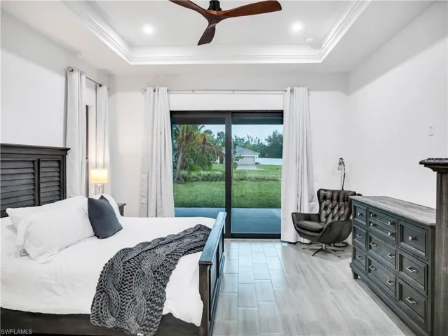 Bedroom featuring access to outside, a raised ceiling, a ceiling fan, and wood tiled floors