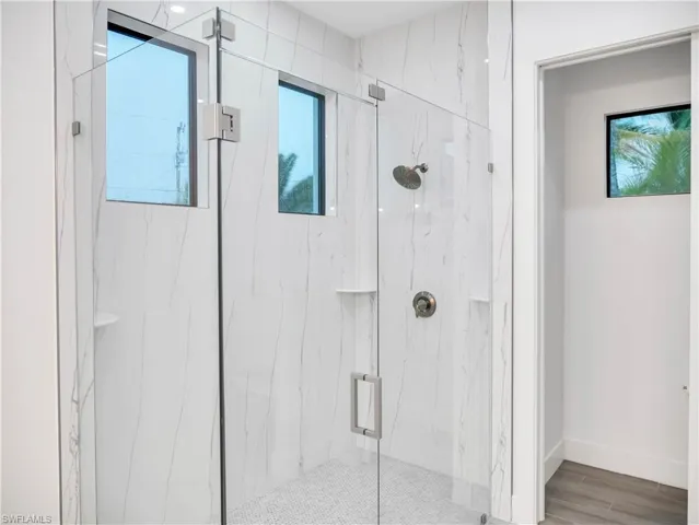 Bathroom with a marble finish shower and wood finish floors