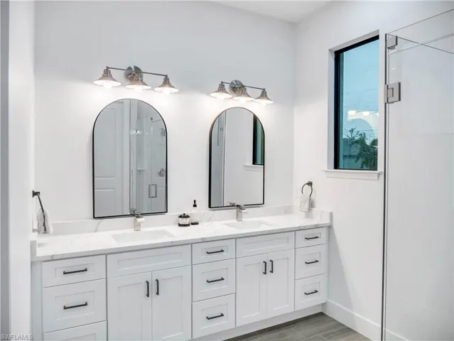 Full bathroom featuring double vanity, a shower stall, and wood tiled floors