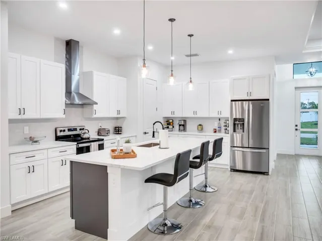 Kitchen featuring stainless steel appliances, white cabinetry, a kitchen breakfast bar, and pendant lighting