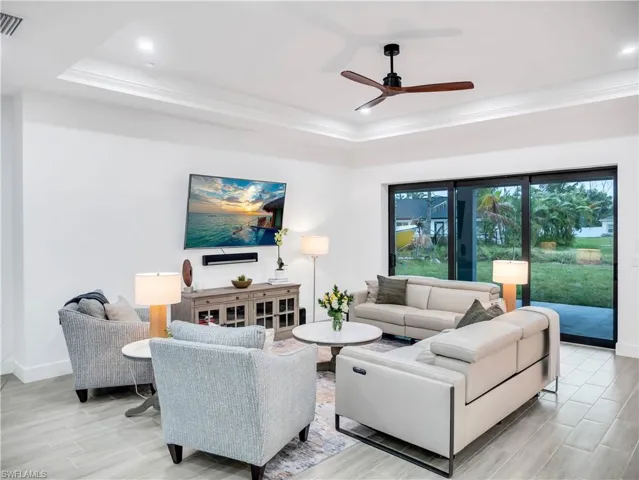 Living area with a ceiling fan, wood tiled floors, ornamental molding, and recessed lighting