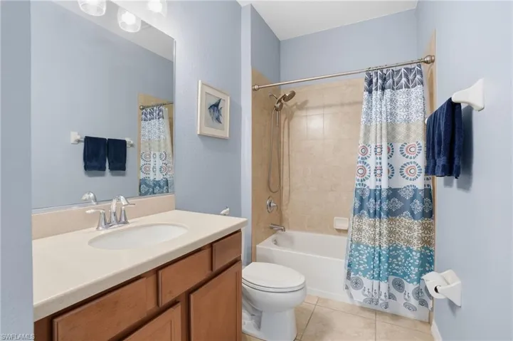 Bathroom featuring vanity, shower / bath combination with curtain, and light tile patterned floors