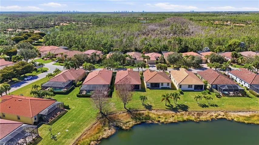 Aerial view of residential area featuring a large body of water and a heavily wooded area