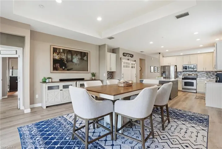 Dining space featuring light wood-type flooring, recessed lighting, and a tray ceiling