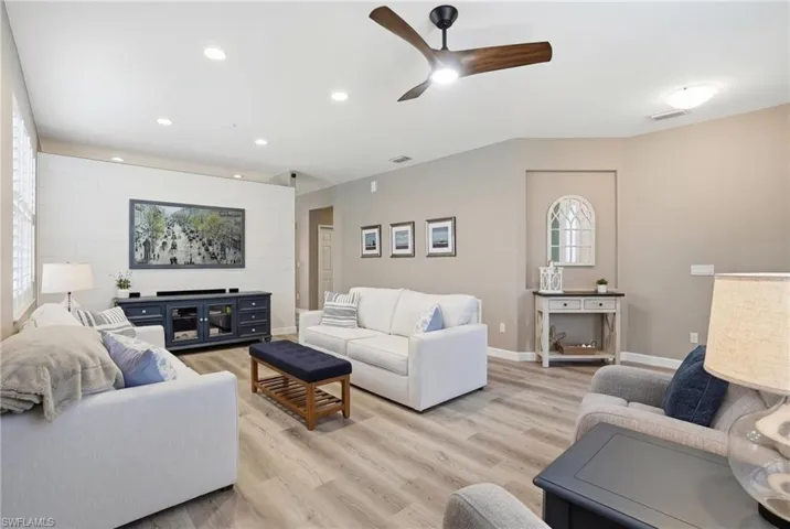 Living room with light wood-style floors, recessed lighting, a ceiling fan, and an accent wall