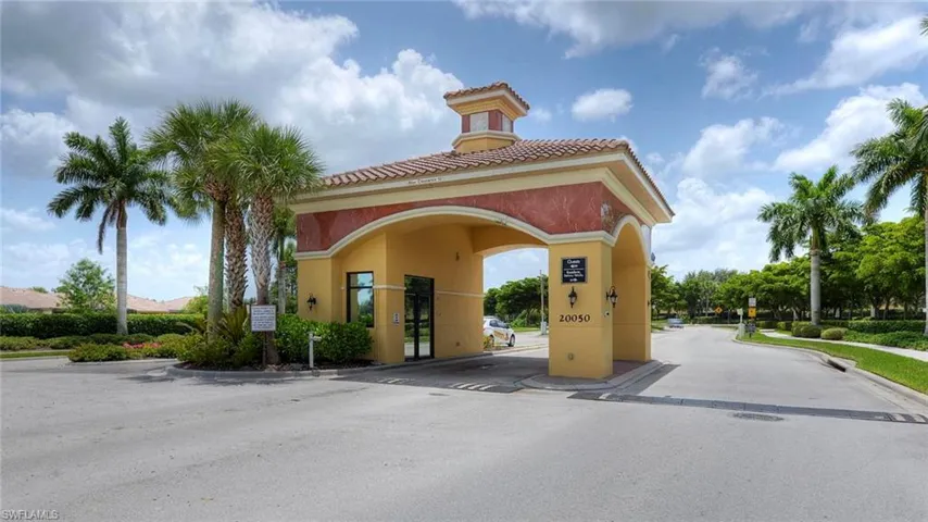 View of asphalt road featuring curbs, a gated entry, and a gate