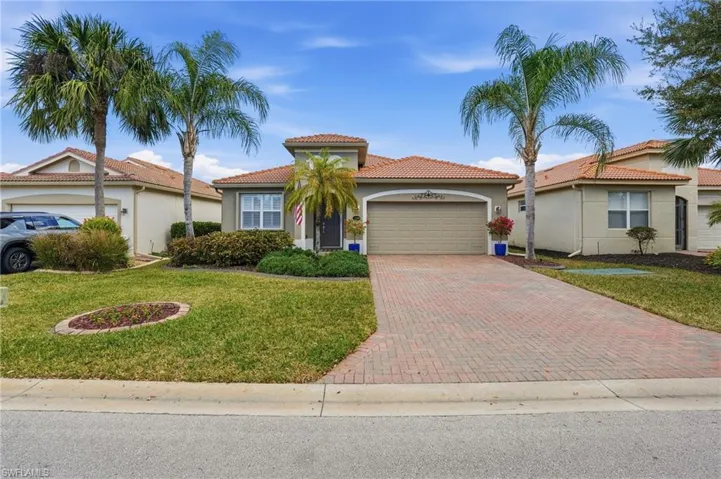 Mediterranean / spanish home featuring a garage, decorative driveway, stucco siding, and a front yard