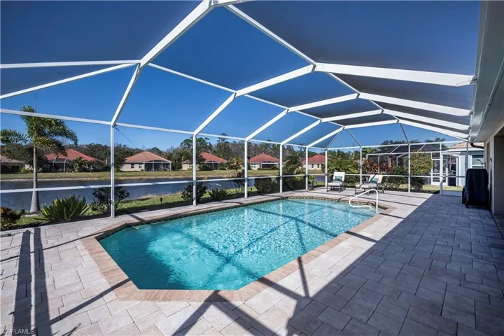 View of swimming pool with a water view, glass enclosure, and a patio area