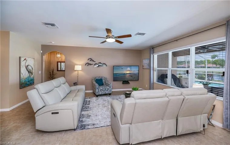 Living area featuring a ceiling fan, arched walkways, and light tile patterned flooring