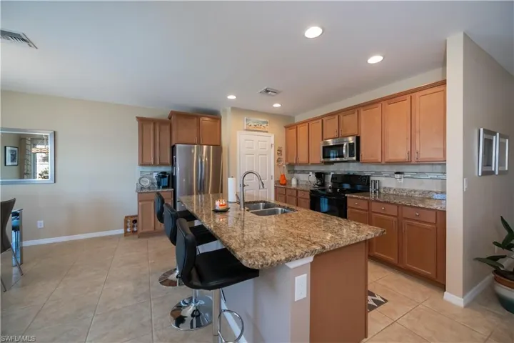 Kitchen with sink, a kitchen bar, stainless steel appliances, and an island with sink