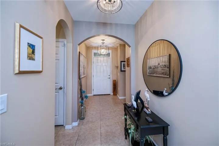 Foyer featuring a chandelier, arched walkways, and light tile patterned floors