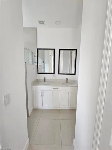 Full bathroom with double vanity and light tile patterned floors