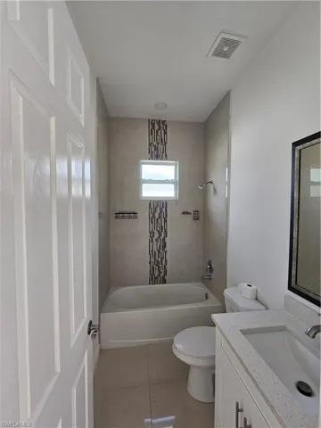 Bathroom with vanity, light tile patterned flooring, and bathing tub / shower combination