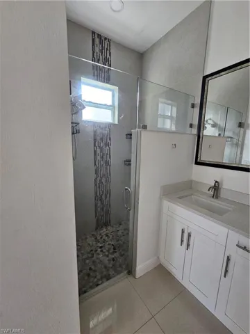 Full bathroom featuring vanity, a stall shower, and light tile patterned floors