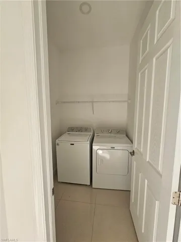 Laundry area with light tile patterned floors and independent washer and dryer