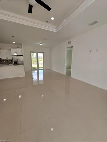 Empty room featuring ceiling fan, a tray ceiling, crown molding, recessed lighting, and light tile patterned floors