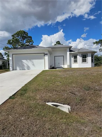 View of front of home with stucco siding, a garage, a front yard, and concrete driveway